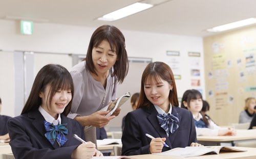 教室で先生と教科書を見る生徒