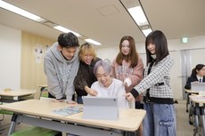 友達とタブレットを見ながら学ぶ生徒たち